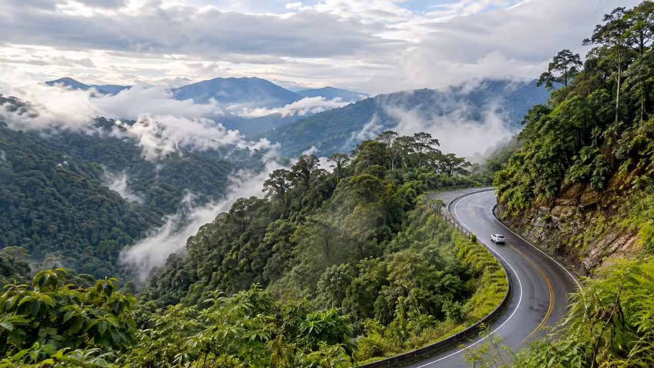 Ilustración fotográfica: Carretera de montaña entre vegetación y nubes